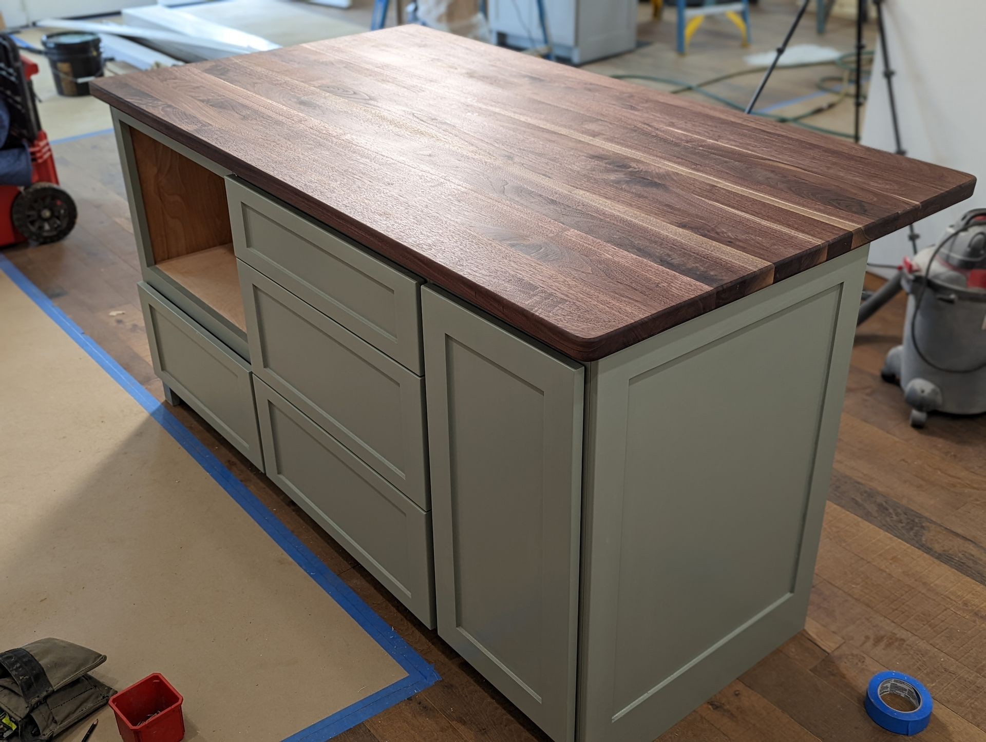 Unfinished kitchen island with wooden countertop and unpainted base in a room under renovation.